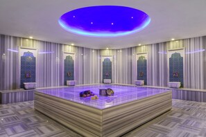 A large, square-shaped room with a central seating area, multiple windows with decorative glass, and a ceiling with a circular light fixture.