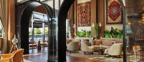 A spacious lobby with high ceilings, large windows, and a seating area with sofas and tables.