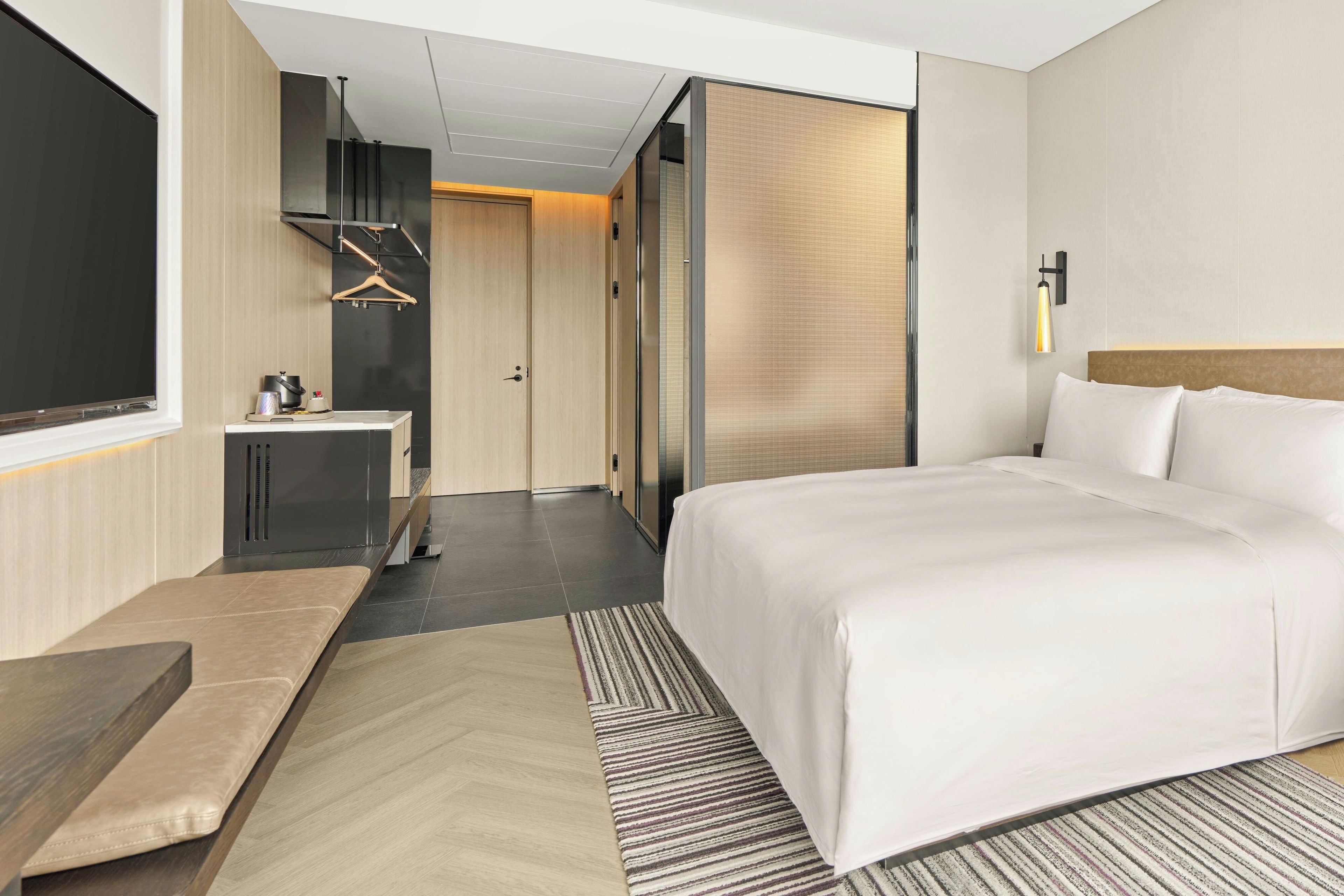 Una habitación de hotel moderna con una cama grande, un escritorio y un vestidor.