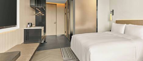 Una habitación de hotel moderna con una cama grande, un escritorio y un vestidor.