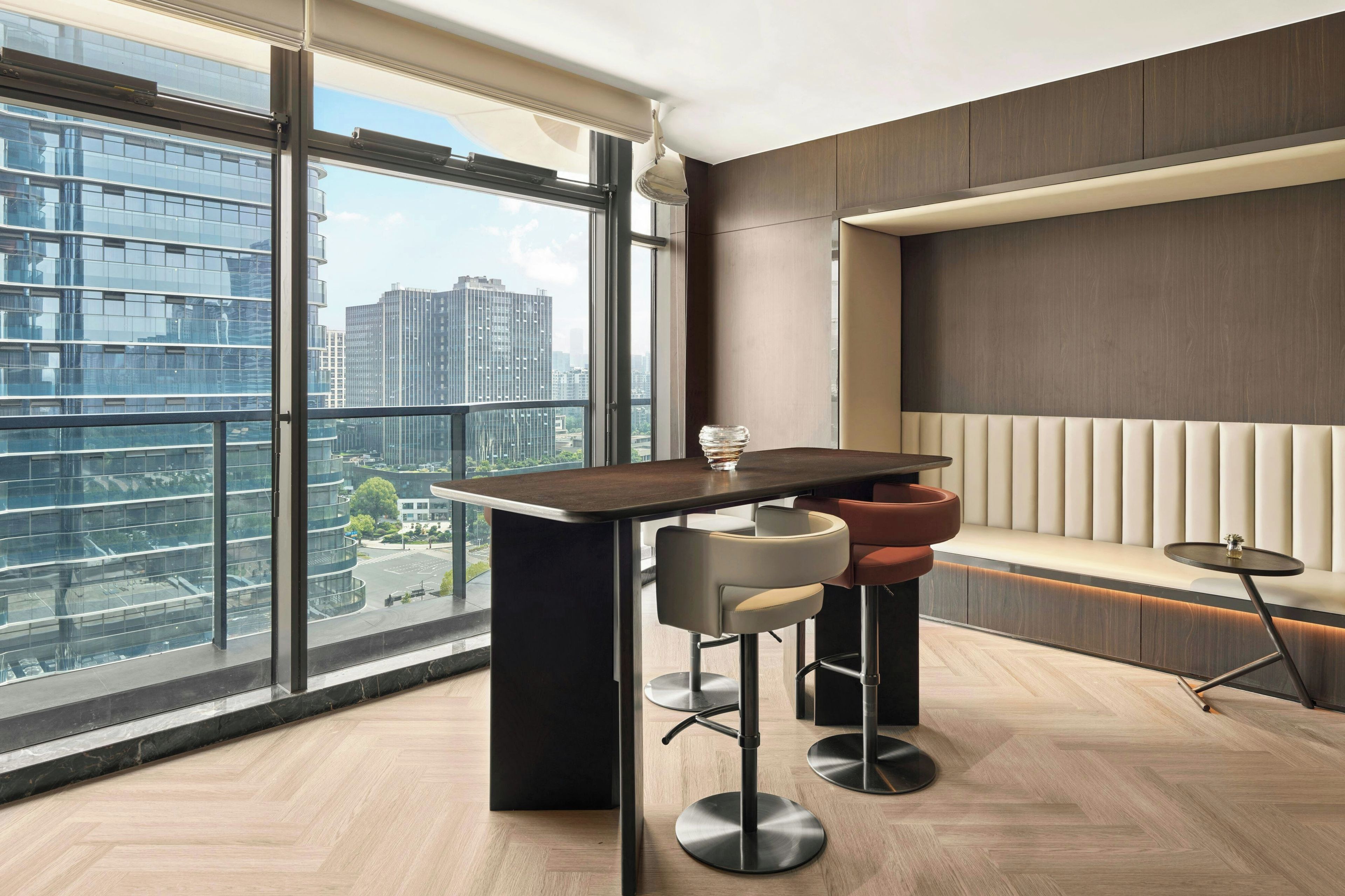 Ein modernes Interieur mit Bar, Sitzgelegenheiten und großen Fenstern mit Blick auf die Stadt.