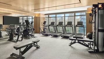 Un gimnasio moderno con cintas de correr, elípticas y equipo de levantamiento de pesas.