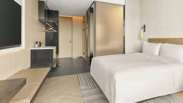 Ein modernes Hotelzimmer mit einem großen Bett, einem Nachttisch, einem Schreibtisch und einem Kleiderschrank.