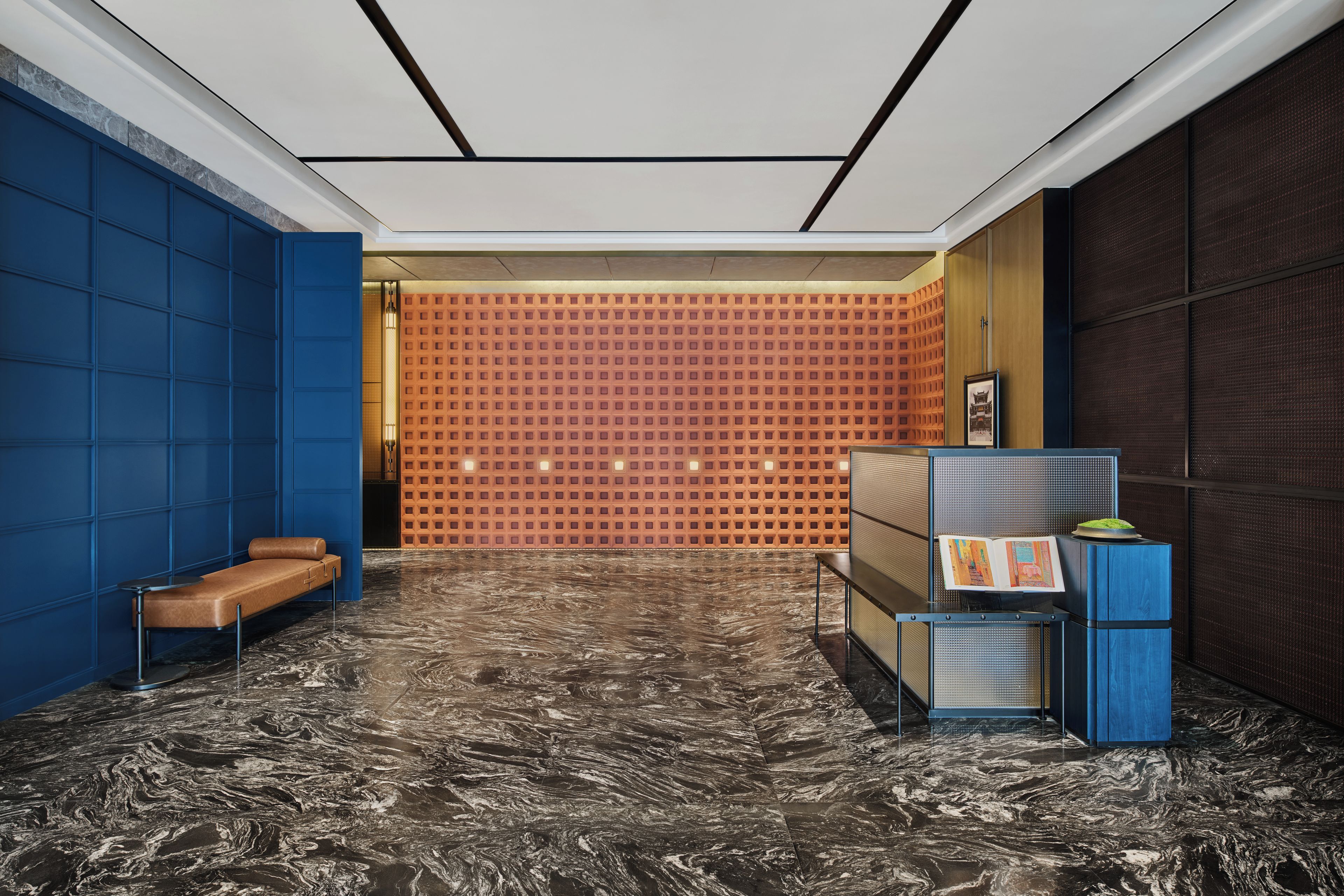Um hall moderno com piso de mármore, área de estar azul e parede estampada.