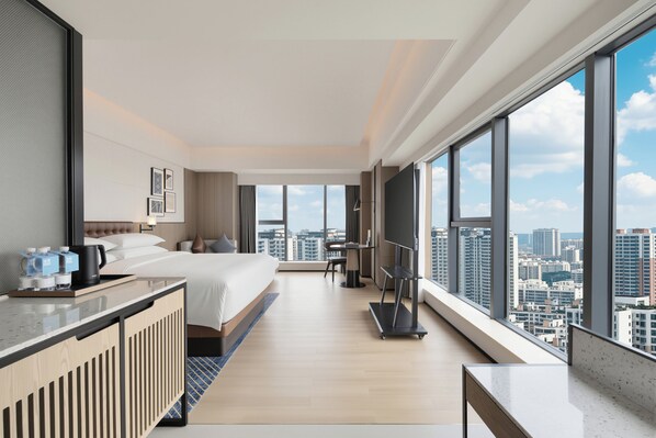 A modern hotel room with a large bed, a desk with a coffee maker, a flat-screen TV, and a city view. - ​Four Points By Sheraton Linyi City Center (Linyi)