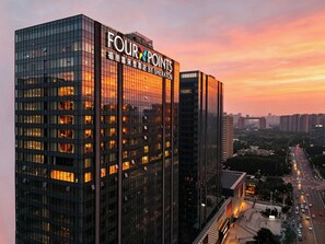 Un edificio de gran altura con ventanas iluminadas y un cartel que dice 'FOUR POINTS'.
