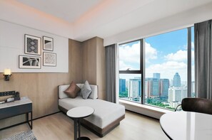 Habitación de hotel moderna con cama, escritorio, silla, una mesita y un ventanal grande con vistas a la ciudad.