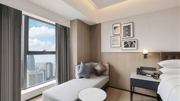Una habitación de hotel con cama, una mesita, una mesita de noche y vistas a la ciudad.