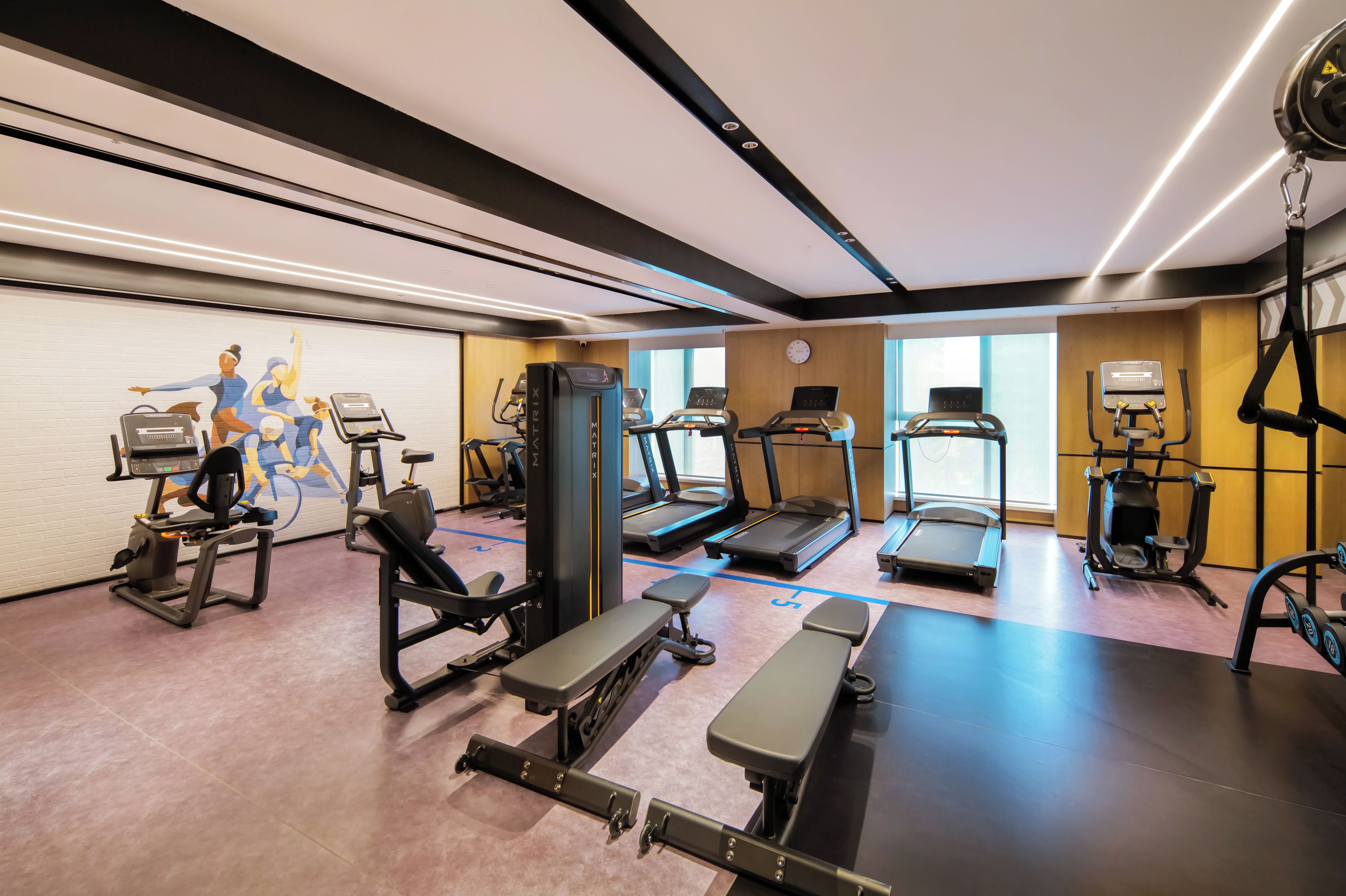 A gym with various exercise equipment, including treadmills, a weight bench, and a rowing machine.