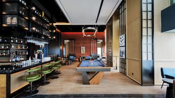 A bar area with a pool table and seating.