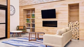 Una sala moderna con un sofá, un televisor, una estantería y una chimenea.