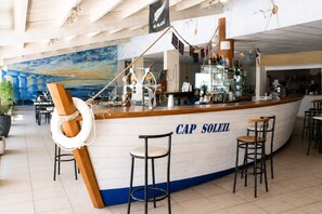 Eine Bar namens 'CAP SOLEIL' im maritimen Stil, inklusive eines Rettungsbojes und eines Schiffsschiffsrades.