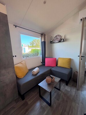 Ein modernes Wohnzimmer mit einer Couch, einem kleinen Tisch und einem Fenster mit Vorhängen.