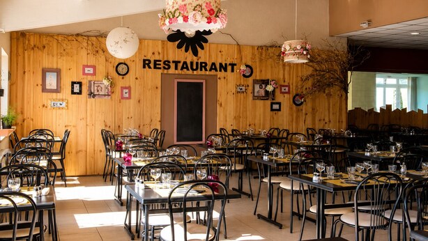Un restaurant amb parets de fusta, diverses taules i cadires.