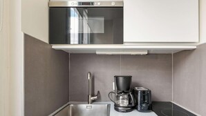 A compact kitchenette with a stainless steel oven, a coffee maker, and a toaster. - Appartement de charme rue des Mauvais Garcons (Paris)