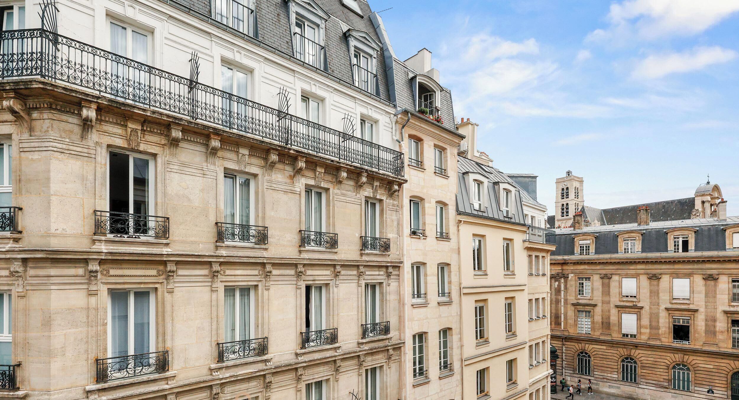 A row of multi-story buildings with balconies, large windows, and classic architectural details.