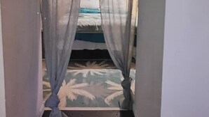 Een smalle doorgang naar een bed met een bedovertrek met dessin.