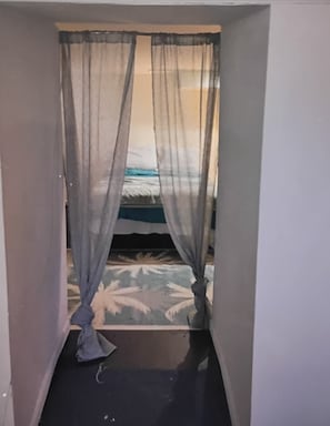 A narrow passageway leading to a bed with a patterned bedspread. - Serene 1-bedroom apartment with AC in Columbus (Columbus)
