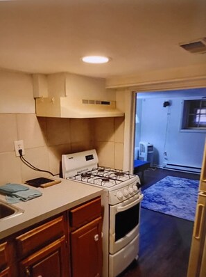 A kitchen with a stove, oven, and wooden cabinets. There is a window and a door leading to another room. - Serene 1-bedroom apartment with AC in Columbus (Columbus)