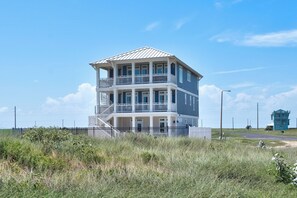 A multi-story building with balconies, a metal roof, and a surrounding fence. - Luxurious Retreat. Ocean Views. Steps to the Beach (Port Aransas)