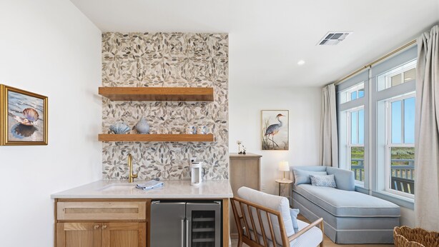 Uma cozinha moderna com máquina de lavar louça embutida, prateleiras de madeira e uma moldura decorativa atrás do fogão.