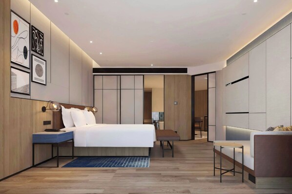 A modern hotel room with a large bed, bedside tables, a desk, and a seating area.