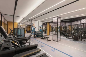 A modern gym with treadmills, weight machines, and a mirrored wall.