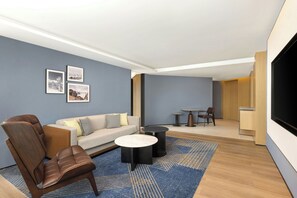 Un saló modern amb un butac armchair de pell, un sofà, una taula de centre i un televisor de pantalla plana fixat a la paret.