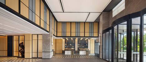 A spacious lobby with a high ceiling, large windows, and a central reception area.