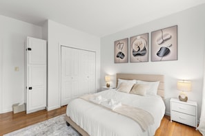 Een slaapkamer met een bed, nachtkastjes, een lamp en een deur.