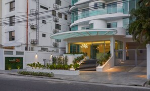 Un hôtel moderne avec une entrée incurvée, un escalier extérieur et une enseigne indiquant qu’il s’agit de Torre Armenia 24.