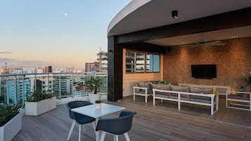 Un espace de vie extérieur moderne comprenant un coin repas, des sièges et une vue sur la ville.