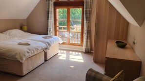 A bedroom with a bed, a small table, and a view of the outdoors through a window.