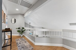 Ein modernes Interieur mit einer Wendeltreppe, einem runden Spiegel und einem Blumentopf.