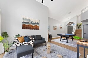 A modern living room with a pool table, a sofa, and a wall-mounted abstract artwork. - Pool + Hot Tub l Game Room l 20 Min to the Strip (Henderson)