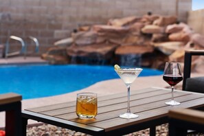 Ein Poolbereich mit einem Tisch, auf dem zwei Gläser und eine Flasche stehen.
