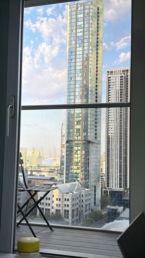 Blick aus einem Fenster auf einen Stadtblick mit Hochhäusern und Baukränen.