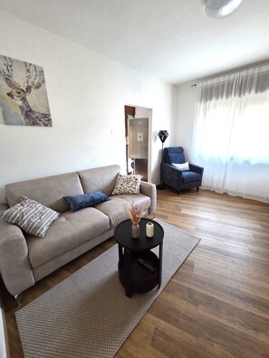 Ein Wohnzimmer mit Sofa, Couchtisch, Sessel und einem Bild an der Wand.