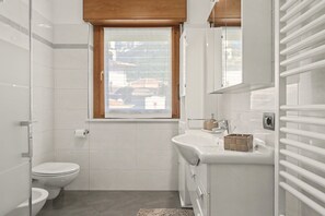Une salle de bain moderne avec des toilettes, un lavabo et une fenêtre.