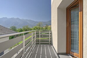 Un balcó amb barana de metall, una porta de fusta i vista a les muntanyes.
