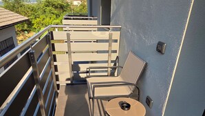 Un balcon avec une balustrade en métal, une table avec des chaises et une vue sur les montagnes.