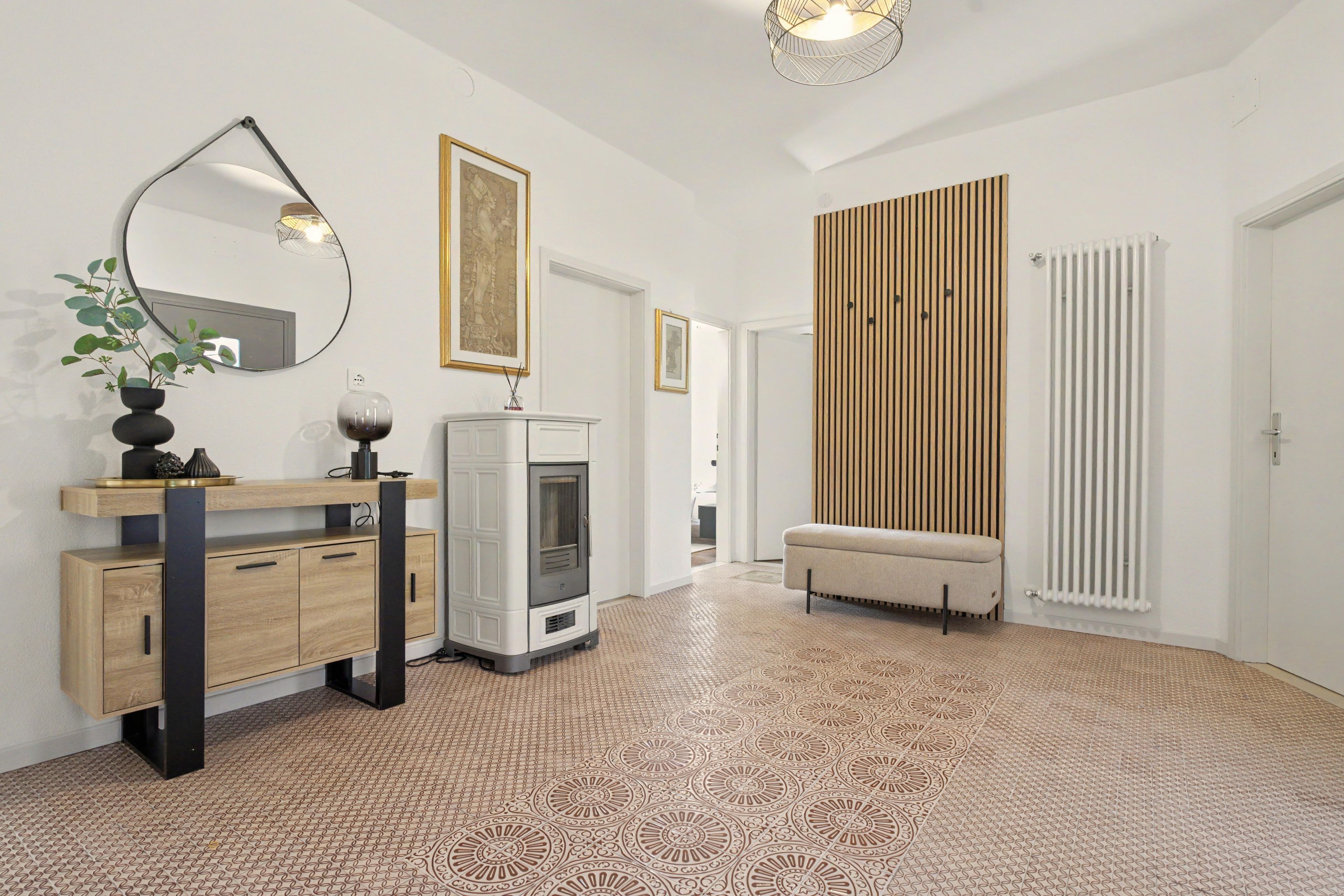 Un intérieur moderne avec un meuble en bois, un miroir, une cheminée, un banc et un sol à motifs.