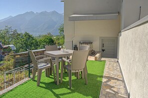 An outdoor patio with a table and chairs, a grill, and a view of mountains. - Apartment 'Casa Elda' with Mountain View, Balcony and Wi-Fi (Vigo di Ton)