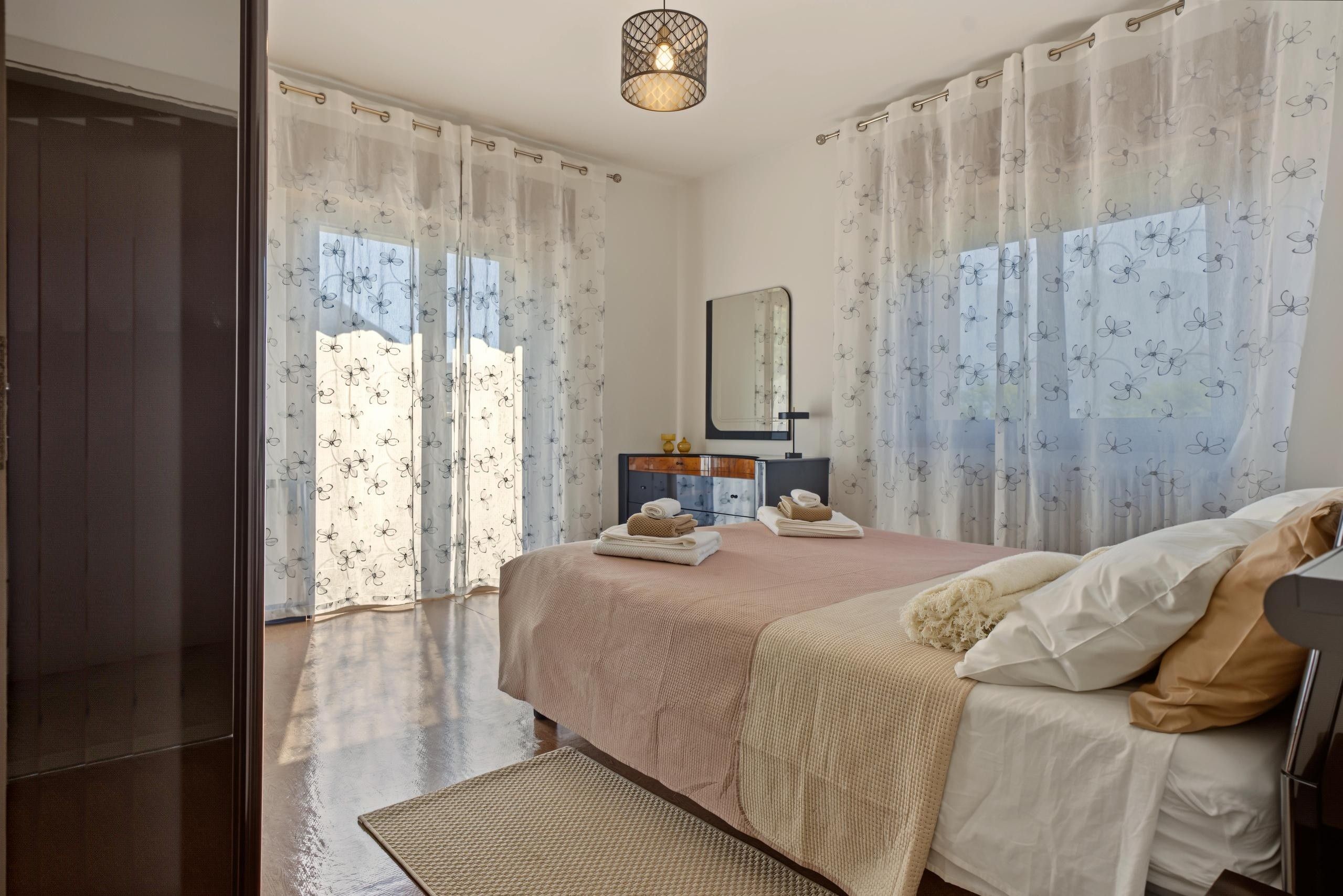 A bedroom with a bed, a bedside table, a mirror, and a wardrobe.