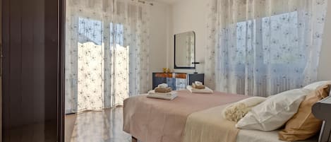 A bedroom with a bed, a bedside table, a mirror, and a wardrobe.