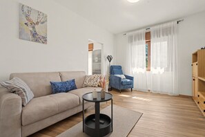 Un saló amb un sofà, una cadira, una taula baixa i un quadre a la paret.