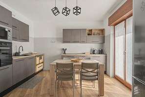 A modern kitchen with a dining area, featuring a built-in oven, microwave, and coffee machine. - Apartment 'Casa Elda' with Mountain View, Balcony and Wi-Fi (Vigo di Ton)