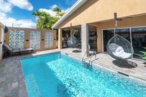 A swimming pool with lounge chairs and a grill area. - Tropical House with Private Pool Near the Ocean (Oistins)