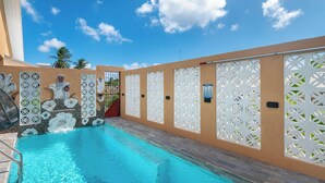 A swimming pool with clear blue water, surrounded by beige walls and white decorative panels. - Tropical House with Private Pool Near the Ocean (Oistins)