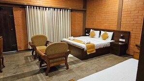 Una habitación de hotel con una cama, una silla, una mesita de noche y una cortina.